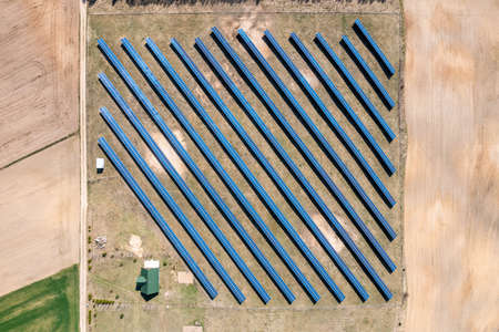 Solar farm aerial view, rows of PV panels by a small houseの写真素材