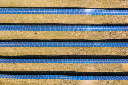 Solar farm aerial view, rows of PV panels by a small house