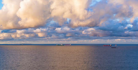 Moody sky over container ships swimming on sea gulf, aerial landscape at duskの写真素材