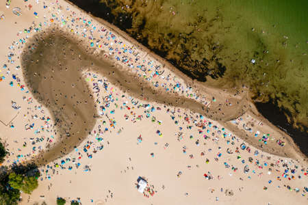 Baltic coast, people having bath in the sea and in the Oliwski stream mouth to the sea during hot summertime weekend, directly above perspectiveの写真素材