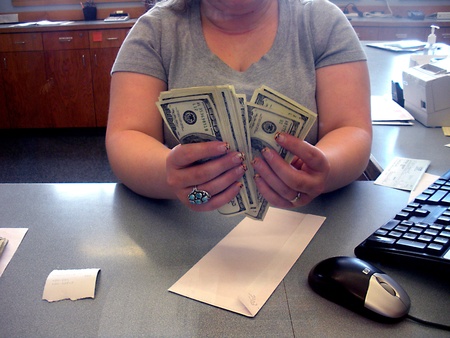 LEWISTON/IDAHO/USA _Female  Cashier countting US Dolloar notes bill at Potlatch Federal Credit Union bank 14 March 2011   のeditorial素材