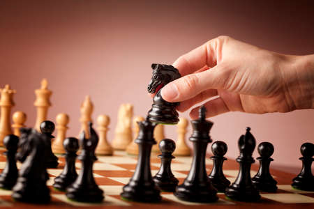 Male hand moving the black chess knight during the game of chessの写真素材