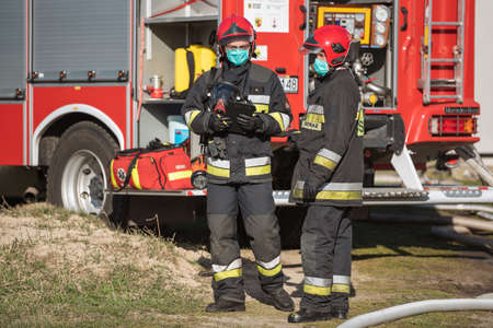DZIESLAW, POLAND - APRIL 6, 20209 - Firefighters with face msk due to Covid-19 during the fire extinguishing action.のeditorial素材