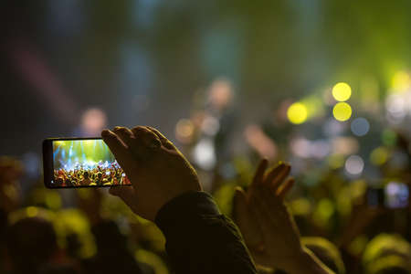Fan holding smartphone and recording or taking picture during a  concertのeditorial素材