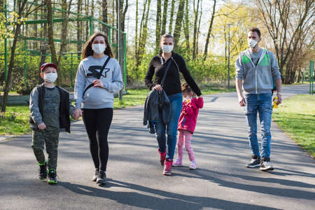 LUBIN, POLAND - APRIL 21, 2020. People with obligatory face masks walking in the park during a pandemic Coronavirus Covid-19.のeditorial素材