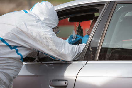Medical staff with face mask and professional uniform takes a swab of the driver's mouth on the...