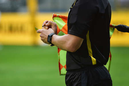 Sideline football referee writing yellow card.