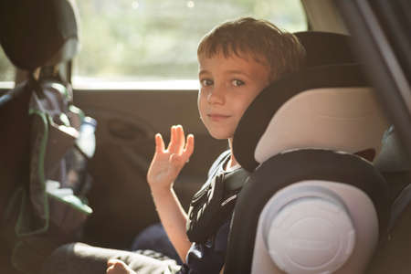 Smiling boy in the car waving goodbye