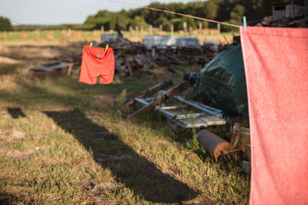 Children's shorts and a towel hang on a clothesline outdoor with village's scenery.の写真素材
