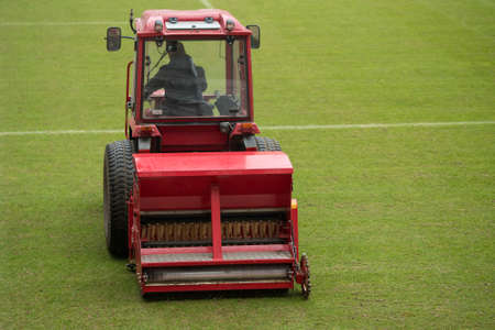 A man in a tractor with a disc seeder drill sowing grass on a football fieldの写真素材