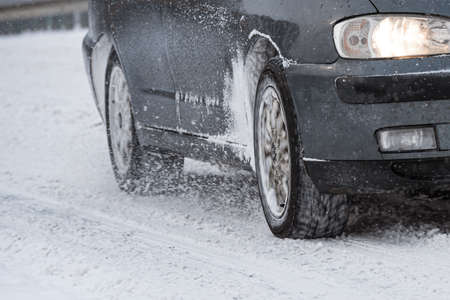 The wheels of a car sliding on a snow-covered roadの写真素材
