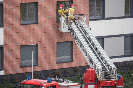 Two firefighters on a ladder try to get to the apartment through the windowの写真素材