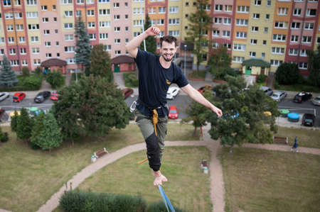 LUBIN, POLAND - SEPTEMBER 25, 2021: VIII Memorial of Iwona Buczek in climbing on difficulty. A smiling tightrope walker is walking on the rope at a high altitude.のeditorial素材