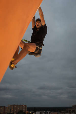 LUBIN, POLAND - SEPTEMBER 25, 2021: VIII Memorial of Iwona Buczek in climbing on difficulty. Young man during climbing and cityscape in the background.のeditorial素材