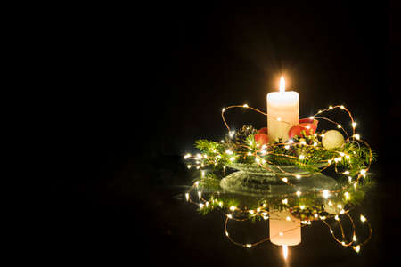 Christmas floral decoration with candle and dark background.の写真素材