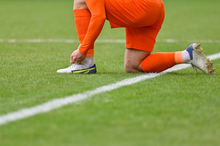 The football player itying his shoe on the turf of the pitchの写真素材
