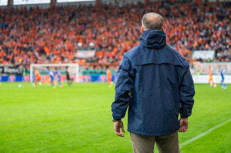 Head coach's back and soccer match at the stadium in the backgroundの写真素材