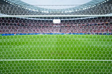 Detail of goal's net and football match in the background.