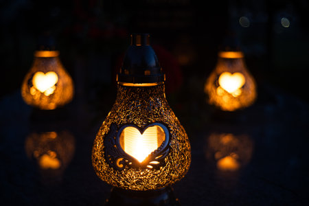 Heart-shaped candles lit on a grave on All Saints' Dayの写真素材