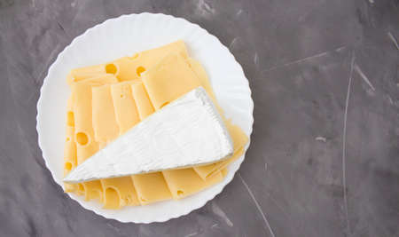 Slices of cheese, medium hard cheese, homemade or Swiss cheese and hard cheese on a white plate. Fresh cheese. View from above. Copyspaceの写真素材