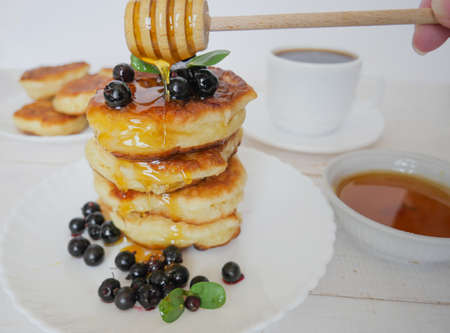 Fritters. Traditional pancakes in a stack on a white plate. Berries and honey. Coffee or teaの写真素材