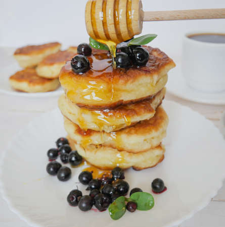 Fritters. Traditional pancakes in a stack on a white plate. Berries and honey. copyspaceの写真素材