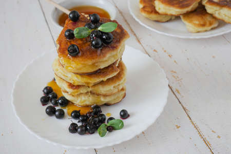 Fritters. Traditional pancakes in a stack on a white plate. White background. Berries and honey. copyspaceの写真素材