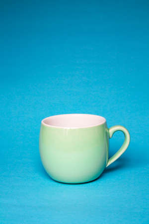 Cup green on a blue background. Tableware or cup for cafes, restaurants. copy spaceの写真素材