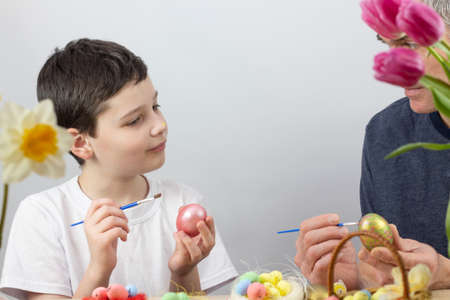 Easter eggs. Happy Easter card. Multicolored Easter eggs. Easter. Easter eggs on a white wooden background. Easter background. Boy painting an eggの写真素材