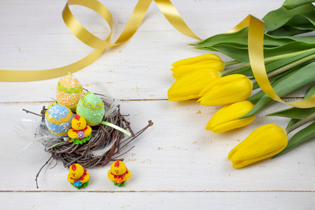 Easter eggs. Happy Easter card. Multicolored Easter eggs. Easter. Easter eggs on a white wooden background. Easter background. Yellow tulipsの写真素材
