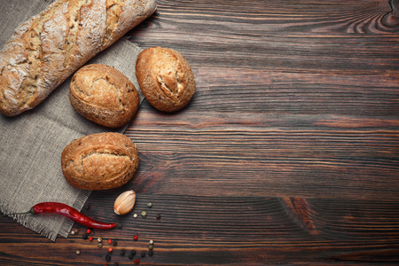 A set of bread, pepper, garlic on a brown wooden boardの写真素材