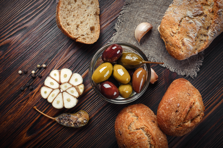 A set of garlic olives capers pepper garlic on a wooden brown tableの写真素材