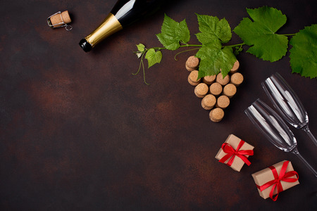 Bottle of champagne, grape bunch of cork with leaves, wineglass gift box on rusty background top viewの写真素材
