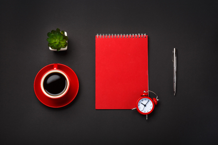 black background red coffee cup note pad alarm clock flowerの写真素材