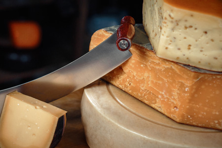 Cheese heads with slices and knives lie on a wooden board with an interior