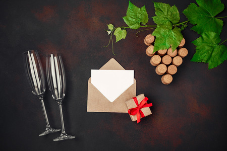 Gape bunch of cork with leaves, two wineglass, cork, envelope and letter on rusty background.の写真素材