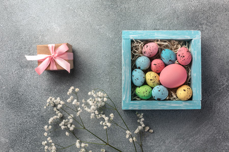 Colorful easter eggs in box and gift on table. Top view with copy spaceの写真素材