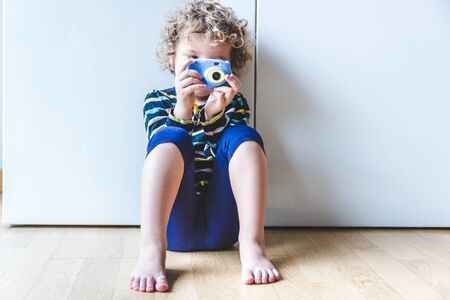 blond little girl sitting on the floor with camera in hand