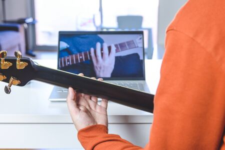 caucasian man learning guitar with a laptoの写真素材