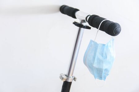 surgical mask hanging from a black scooter handle bar. Selective Focus. Protection during covid19...