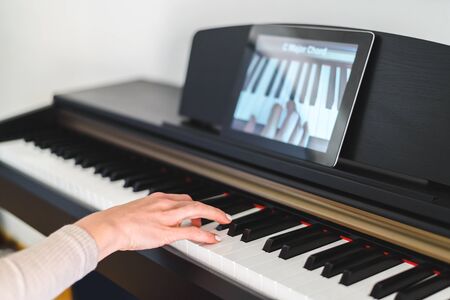 caucasian woman learning to play piano with video lessons. Concept of virtual learning