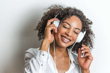 attractive afro-american woman smiling enjoying music with white headphones