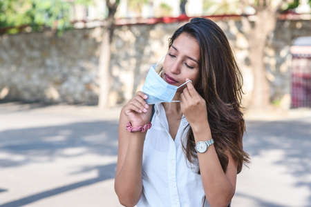 beautiful indian model with white shirt putting on a surgical mask in the street in order to follow...