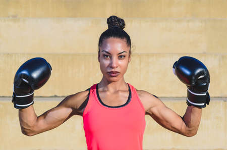 young attractive afro american boxer woman wearing black and pink sportswear looking at the camera...