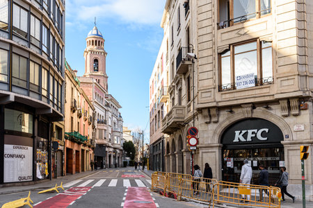 Sabadell - Catalonia, SPAIN - January 31st of 2021: view of Via Massague avenue from Placa de l'Angel square intersection and Kentucky Fried Chicken restaurant in the foregroundのeditorial素材