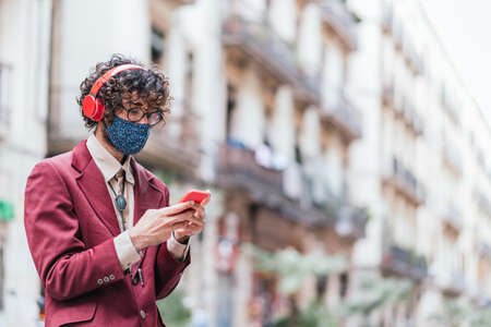 Young caucasian trendy man using a red phone in the street