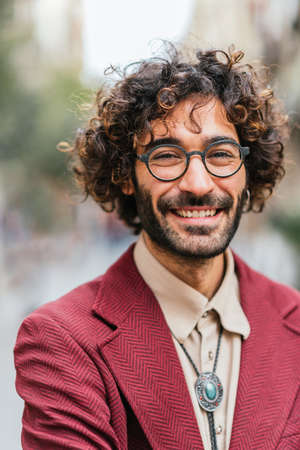 Close up portrait of a fashionable and handsome caucasian man smiling in the streetの写真素材