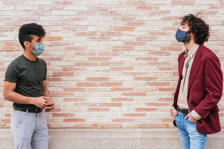 Caucasian and latin friends keeping social distance in the streetの写真素材