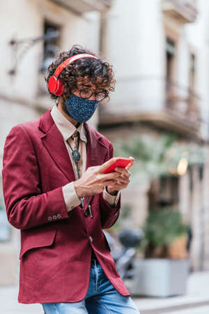 Young caucasian trendy man using a red phone in the street