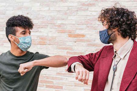 caucasian and hispanic friends greeting each other with elbowsの写真素材